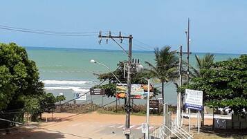 Uma estrada costeira com vista para o oceano, linhas de energia e várias placas.