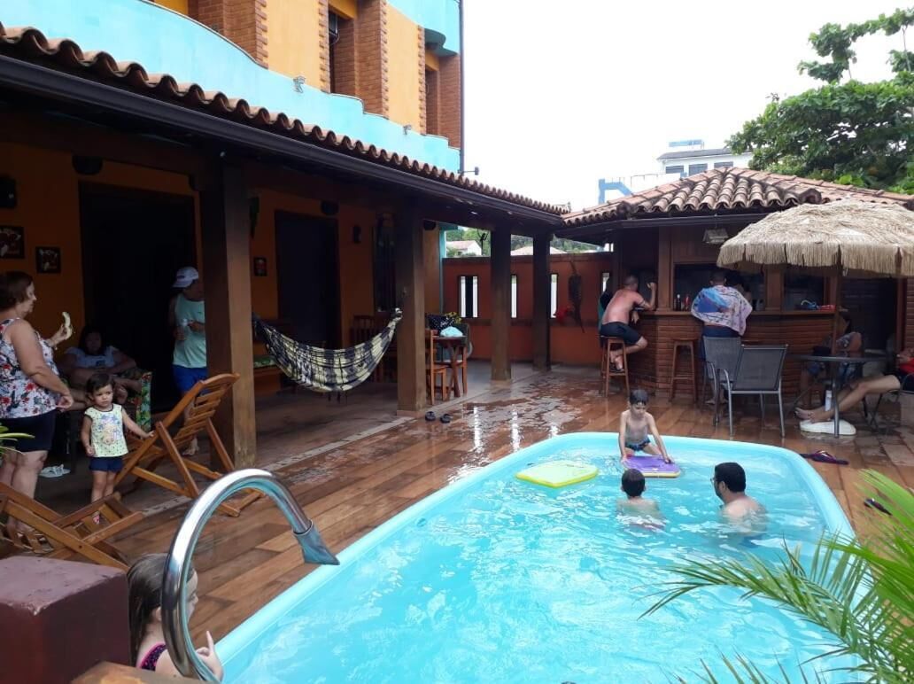 Área de piscina com deck revestido, espreguiçadeiras e estrutura de telhado de palha.