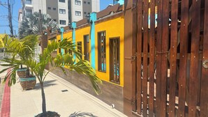A building with a yellow facade, wooden gate, and potted plants. - Pousada Maravista (Anchieta)