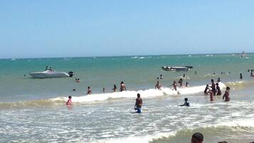 Uma praia com pessoas nadando e um barco na água.