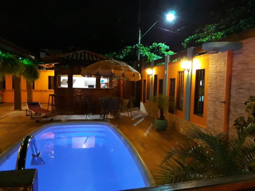 Una piscina con zona de bar, sillas de descanso y una estructura de techo de paja.