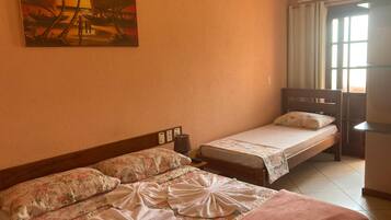 A hotel room with two beds, a painting of palm trees, a window with curtains, and an air conditioning unit.