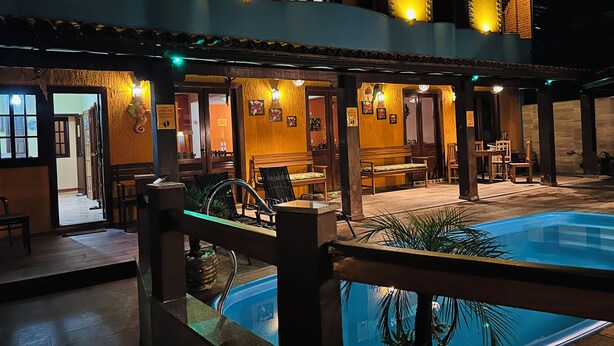 A hotel with a pool, outdoor seating, and a covered patio area. - Pousada Maravista (Anchieta)