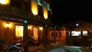 A hotel courtyard with a swimming pool, outdoor seating, and a thatched-roof structure. - Pousada Maravista (Anchieta)