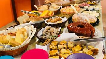 Een buffet met diverse gerechten, waaronder brood, gebak en desserts.