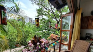 A balcony with a wicker chair, a table with a bottle and glasses, and colorful hanging decorations. - Casa Tortuga @ Selva Romantica (Puerto Vallarta)