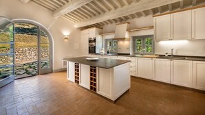 Een moderne keuken met een centraal eiland, witte kasten en uitzicht op een stenen muur.