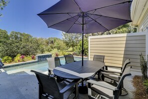 Un patio al aire libre con piscina, una mesa y sillas, y un paraguas grande.