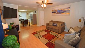A living room with a sofa, a coffee table, a TV, and a ceiling fan. - Home Sweet Home - Peace, Love, & Enjoy (Kingsville)