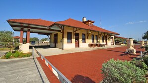 A building with a red-tiled roof, a covered waiting area, and a brick-paved entrance. - Home Sweet Home - Peace, Love, & Enjoy (Kingsville)