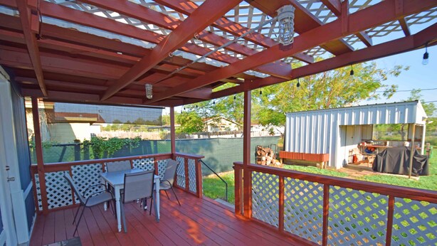 A covered deck with a red floor, white lattice railing, and a table with chairs. - Home Sweet Home - Peace, Love, & Enjoy (Kingsville)