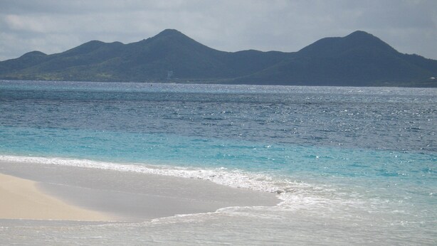 A beach with clear turquoise water and a sandy shore.