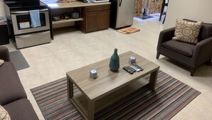 A compact living space with a kitchenette, a sofa, a coffee table, and a patterned rug.