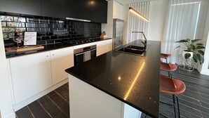 A modern kitchen with black countertops, white cabinets, and a central island.