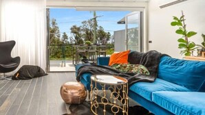 A modern living room with a blue sofa, a black chair, a round coffee table, and a unique gold-patterned side table.