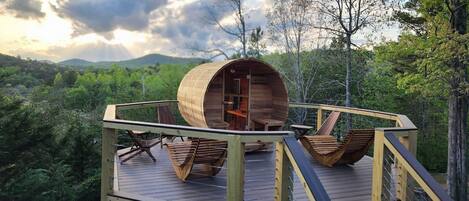 Una cabaña de madera con interior circular, rodeada por una terraza con asientos.