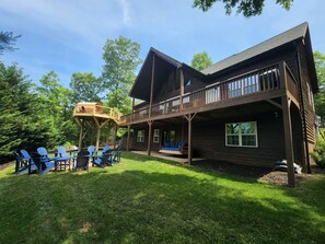 A wooden cabin with a deck, outdoor seating, and a swing.