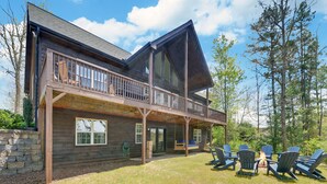 Une cabane en rondins dotée d’un balcon et d’un espace extérieur aménagé pour s’asseoir.
