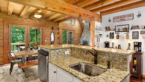Una cocina con encimeras de granito, pileta de acero inoxidable, vigas de madera y chimenea de piedra.