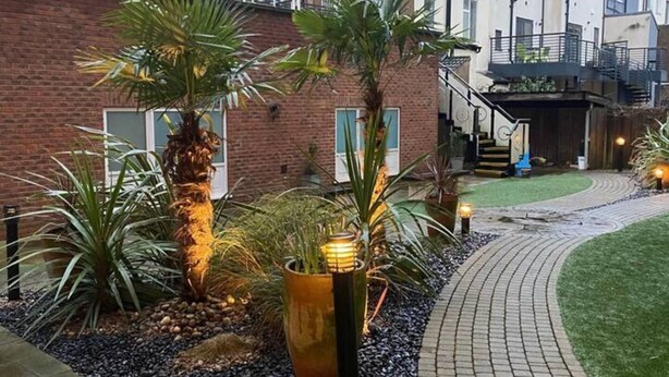 A courtyard with a brick building, palm trees, and a pathway. - Apartment-sleeps4-balcony-parking-petsok (Hull)