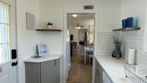 Una cocina moderna con armarios blancos, piso de madera y un comedor con mesa y sillas.