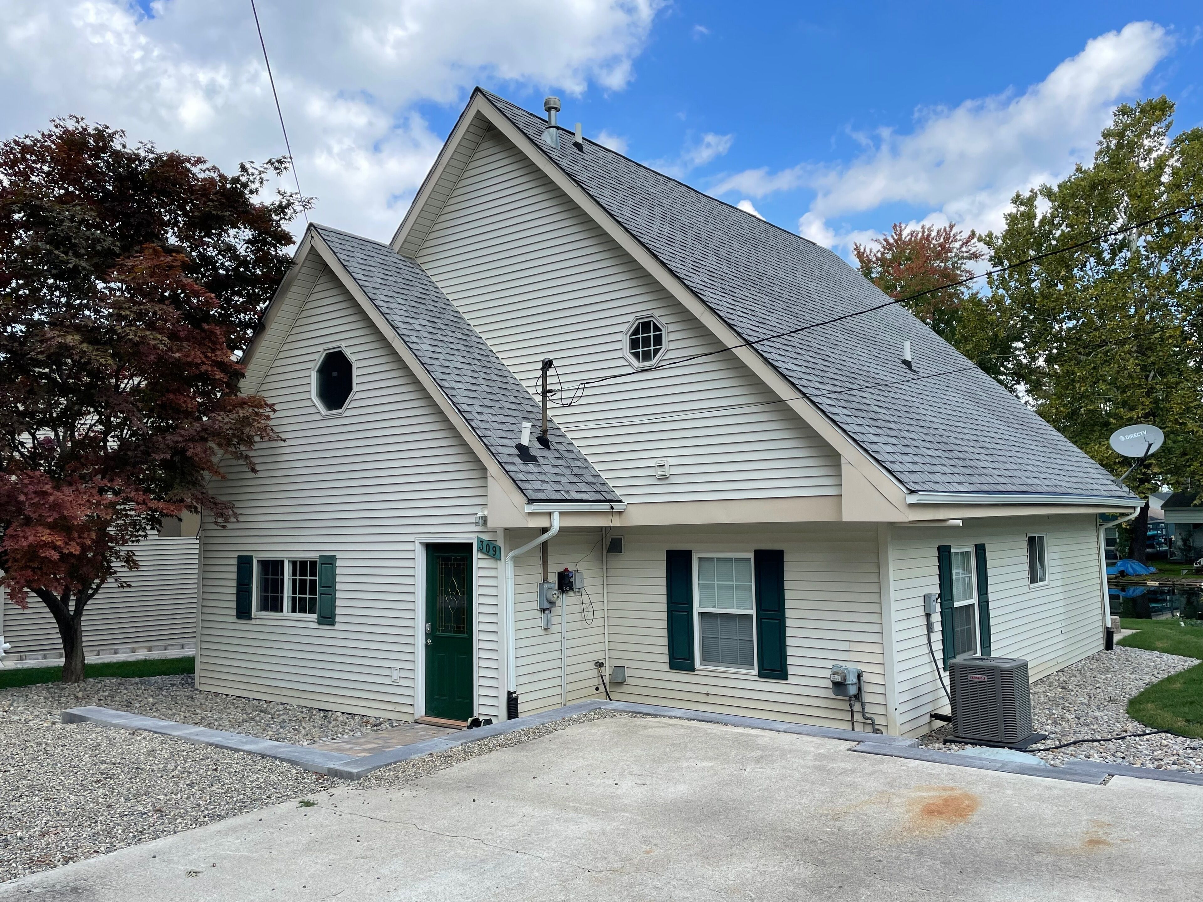 A two-story house with a gabled roof, a satellite dish, and a small front porch.