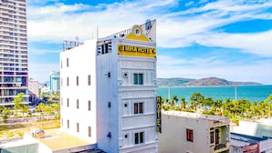 Un edificio blanco con un letrero amarillo que dice "MIRA HOTEL" y vista al océano.