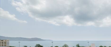 A coastal cityscape with a view of the sea and mountains in the distance.