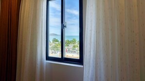Una habitación con un ventanal que ofrece vistas al mar y edificios lejanos.