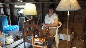 A rustic room with a spinning wheel, a table with yarn, and a lamp. - Farmstay, 2 bedrooms with 2 private baths, private entrance. (Waldoboro)