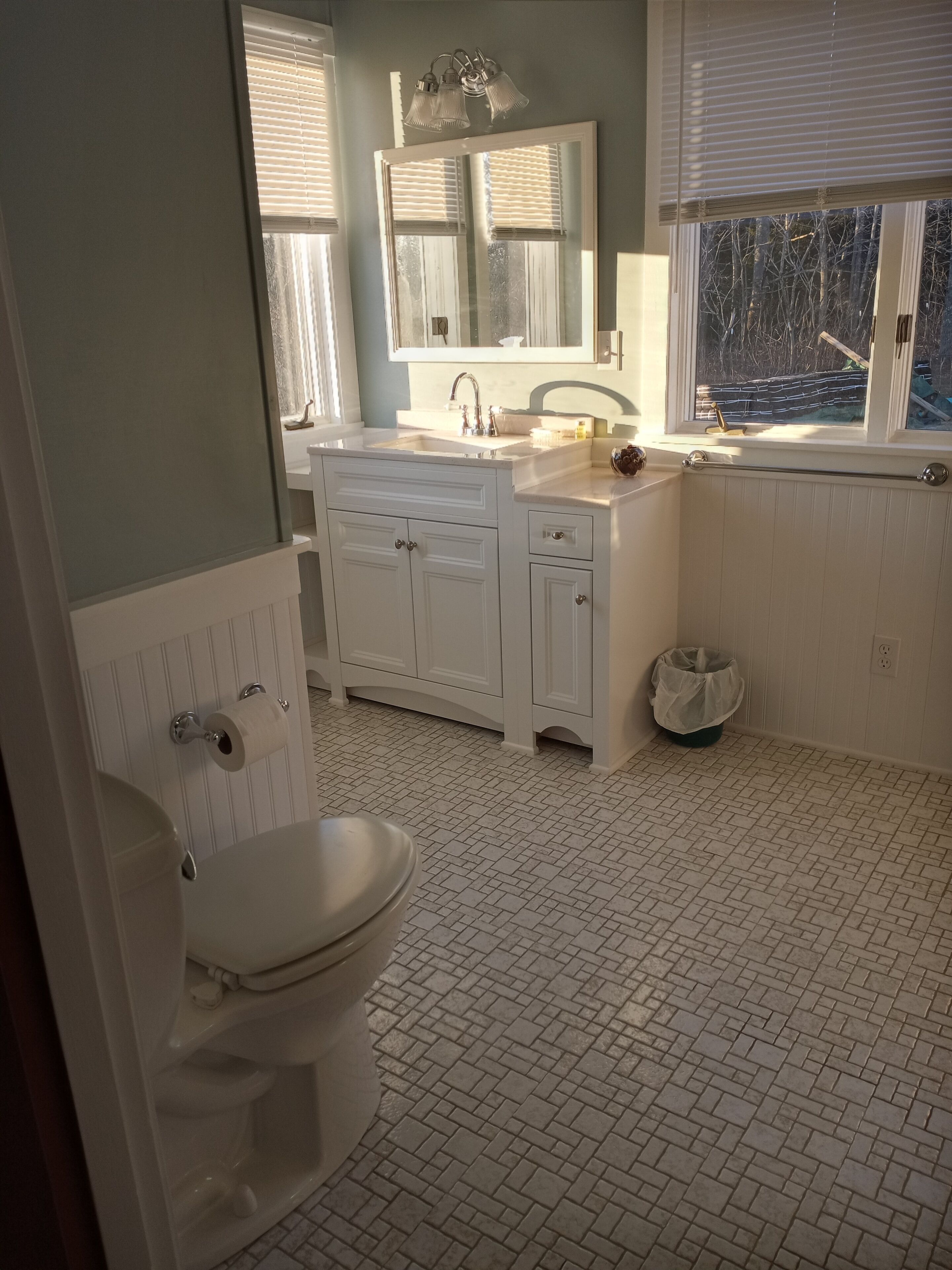 A bathroom with a toilet, sink, and window.