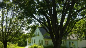 A house with a large tree in front, a porch, and a well-maintained lawn. - Farmstay, 2 bedrooms with 2 private baths, private entrance. (Waldoboro)