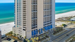 Un hôtel de grande hauteur, avec de nombreux étages, offrant une vue sur la plage et disposant d’un parking avec une route menant à la plage.