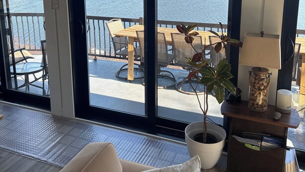 Een kamer met een grote schuifglazen deur die uitkomt op een terras met uitzicht op een wateroppervlak.