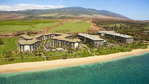 Un complexe hôtelier comprenant plusieurs bâtiments, une plage et un paysage montagneux en arrière-plan.