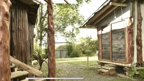 A rustic wooden building with a porch and a stone wall. - The round house in Filandia with waterfall (Filandia)