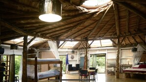 A rustic wooden interior with bunk beds, a dining area, and a large window providing natural light. - The round house in Filandia with waterfall (Filandia)