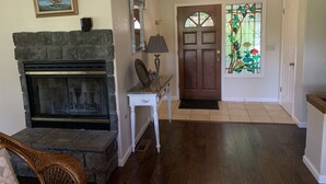Una sala de estar con chimenea, un banco de piedra y una silla de mimbre.
