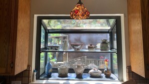 Una cocina con armarios de madera, una ventana de vitral y diversos utensilios de cocina exhibidos en estantes.
