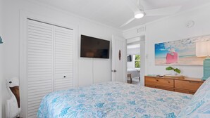 A bedroom with a bed, a television, a dresser, and a painting of a beach scene. - Bluewater Beach House will not disappoint (Fort Myers Beach)