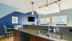 A kitchen with a granite countertop, stainless steel sink, and wooden cabinets.