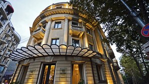 A historic building with a curved facade, a balcony, and a sign indicating it is a hotel. - Astoria Tbilisi (Tbilisi)