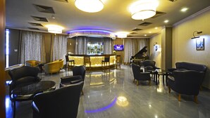 A hotel lobby with a bar area, seating, and a piano. - Astoria Tbilisi (Tbilisi)