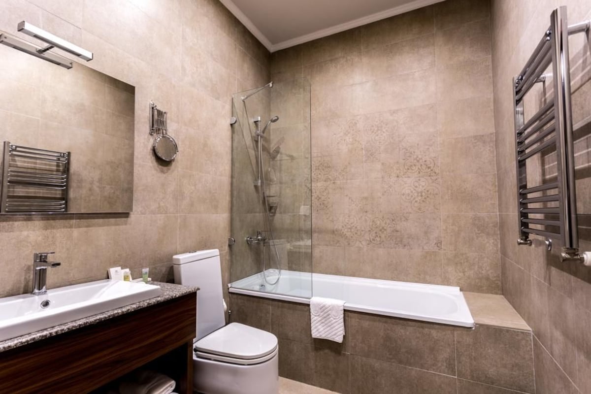 Un baño moderno con ducha envuelta en vidrio, bañera, inodoro y tocador con lavabo.