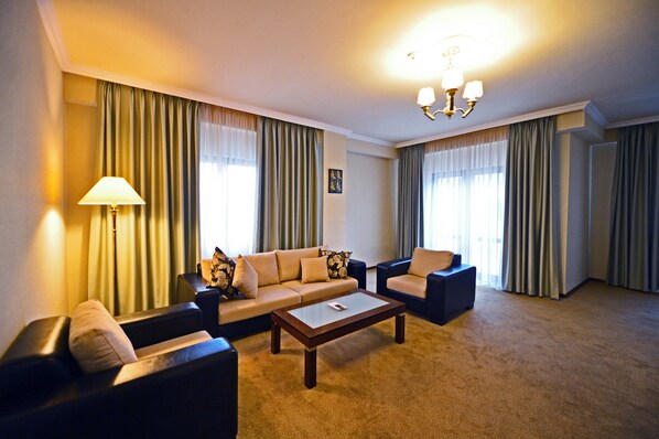 Quarto de hotel com um sofá, uma mesa de centro e uma luminária.