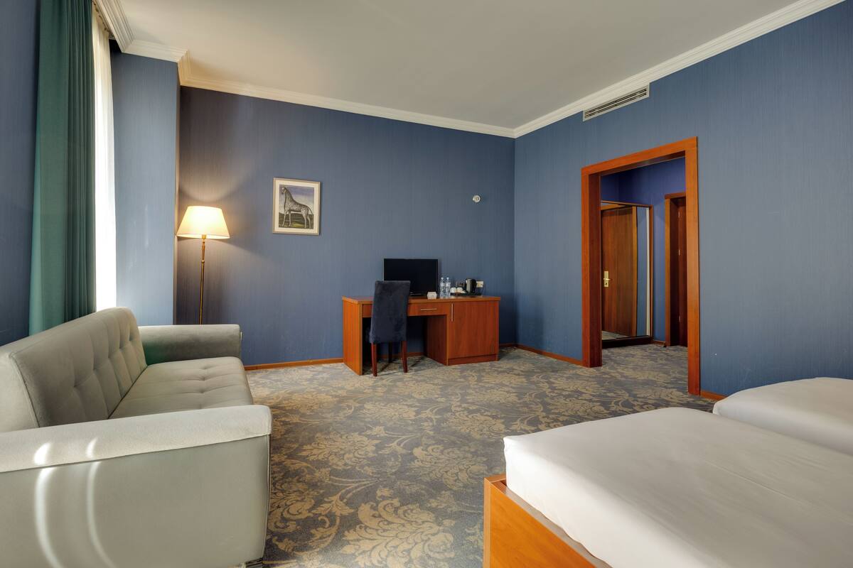 Ein Hotelzimmer mit Sofa, Bett, Schreibtisch und Stuhl.