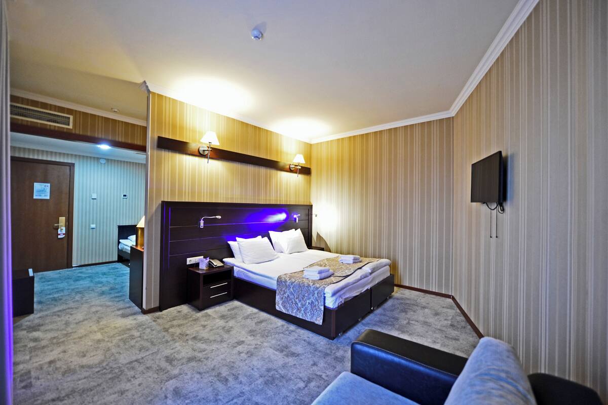 Ein Hotelzimmer mit einem großen Bett, Nachttischen, einem Fernseher und Teppichboden.