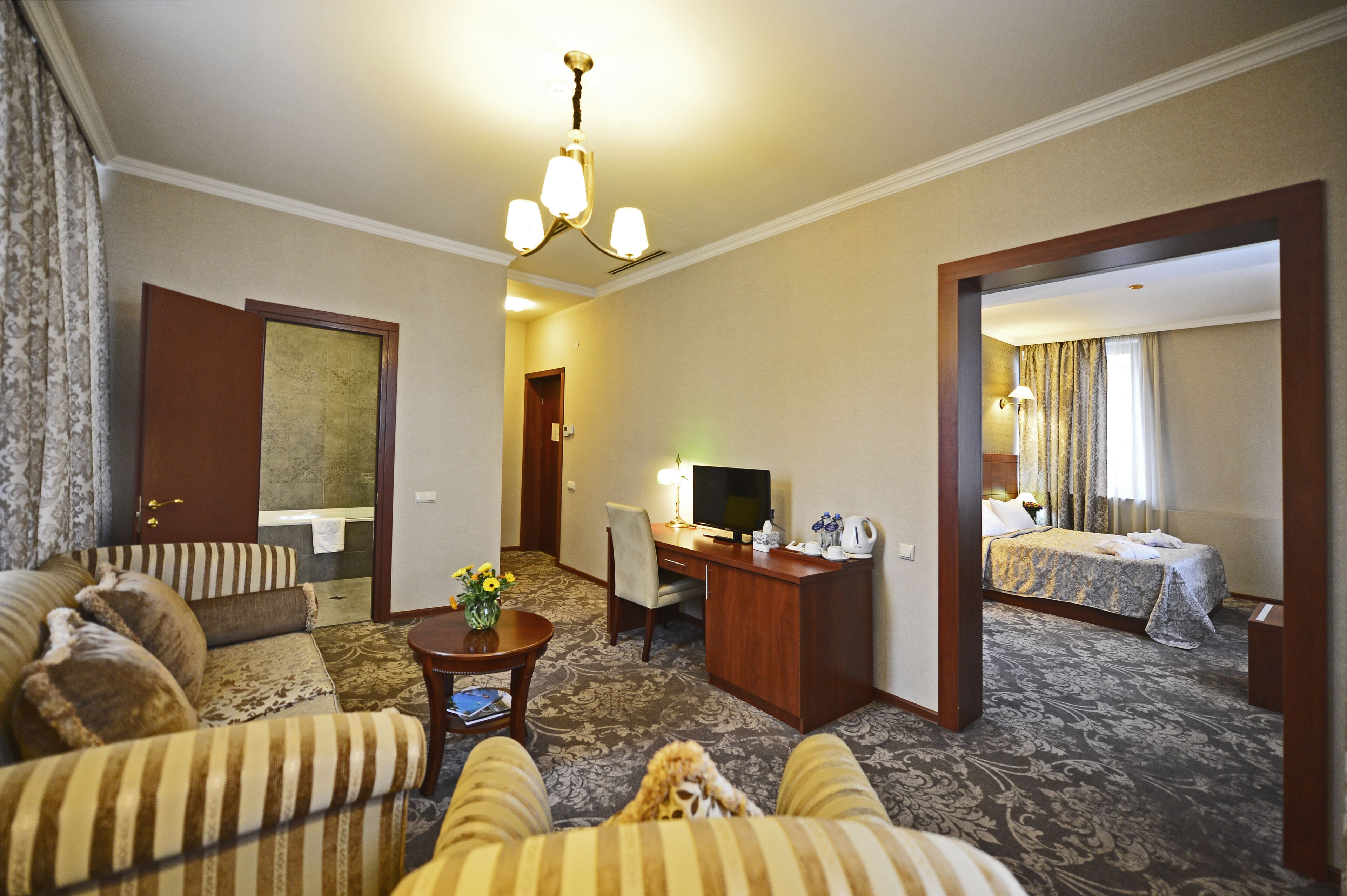 A hotel room with a sofa, a desk with a computer, a bed, and a carpeted floor.