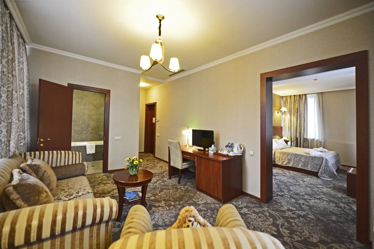 Ein Hotelzimmer mit Sofa, Schreibtisch mit Computer, Bett und Teppichboden.