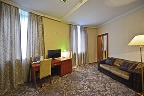 A hotel room with a desk, a television, a sofa, and a lamp. - Astoria Tbilisi (Tbilisi)